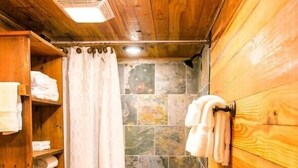 A wooden bathroom with a shower, toilet, and a small sink. - Waterfront, 100 Year-Old wood Cabin - #16 (Charlotte)