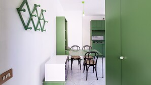 A dining area with a white table and four chairs, green cabinets, and a green wall decoration. - VILL' ANDREA (App. 7) (Cecina)