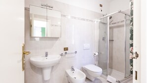 A bathroom with a sink, bidet, toilet, and glass shower enclosure. - VILL' ANDREA (App. 7) (Cecina)