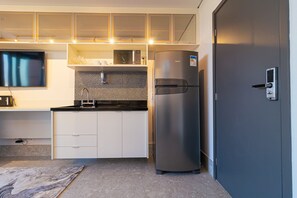 Eine kompakte Küche mit integriertem Mikrowellenherd, einem Edelstahlkühlschrank und einer dunkel gefärbten Tür.