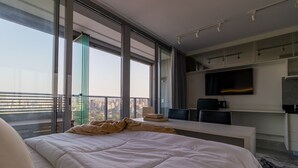 Een moderne hotelkamer met een groot bed, een bureau, een flatscreen televisie en een balkon met uitzicht over de stad.