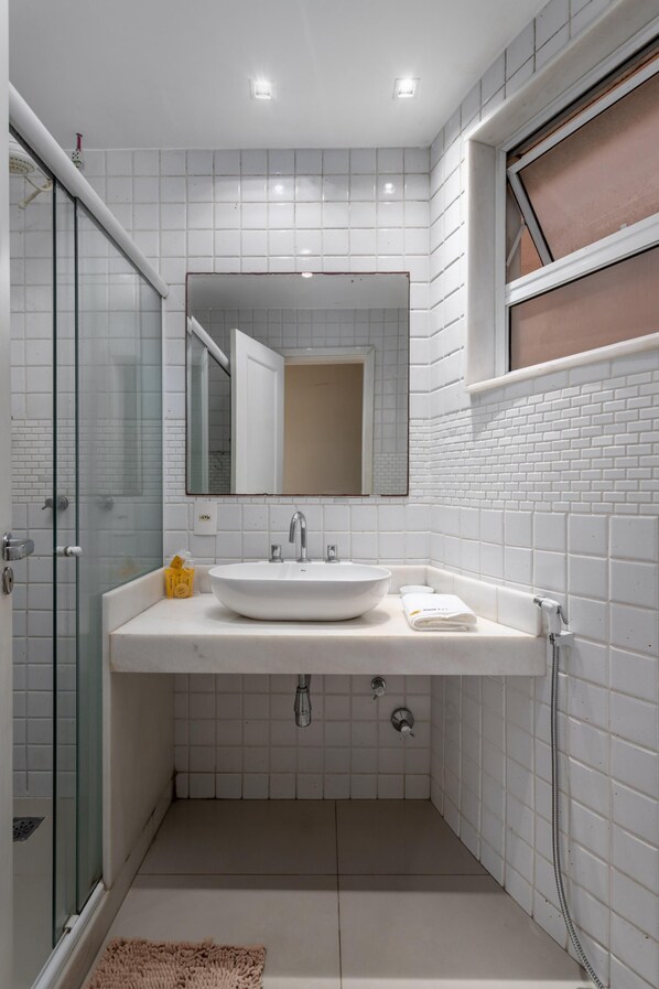 Une salle de bain moderne avec un lavabo blanc, un miroir et une douche en verre.