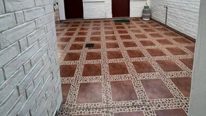 A courtyard with a patterned tile floor, white brick walls, and two dark-colored doors. - Cozy Suit!viajeros y Mujeres 100% Seguras!céntrico (Quito)
