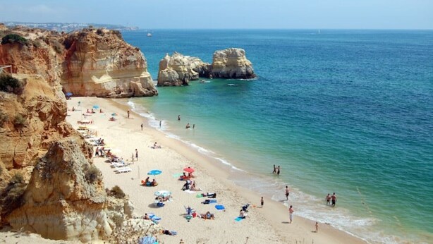 A coastal beach with rocky cliffs and clear blue waters. - Praia da Rocha 2 bedroom beach side apartment (Portimão)