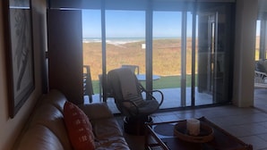 A living room with a large sliding glass door leading to a view of the beach. - New Listing...Beachfront Ground Floor - Steps to Beach, Unbelievable Views!!! (South Padre Island)