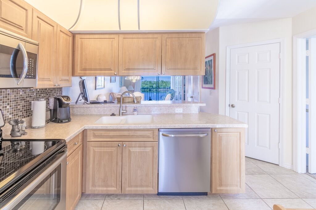 A modern kitchen with wooden cabinets, a stainless steel dishwasher, and a large island with a sink.