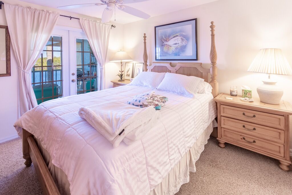 Une chambre à coucher avec un grand lit, une table de chevet, une lampe et un tableau au mur.
