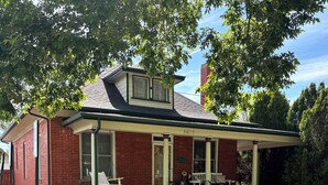 A red brick house with a porch, number 5618, and a small garden area. - Historic, Unique, Walkable, Rail to Denver, Red Rocks (Arvada)