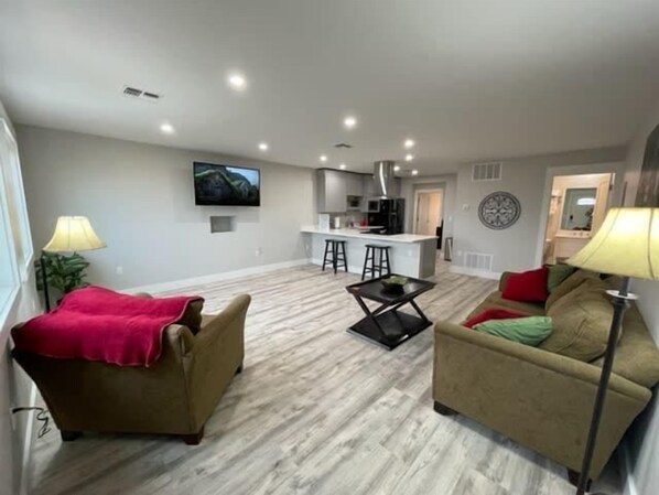 A modern living room with a sofa, a coffee table, and a TV mounted on the wall.