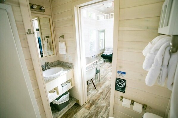 A wooden cabin-style bathroom with a sink, mirror, and towel rack.