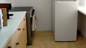 A compact kitchen with a white refrigerator, a built-in oven, and wooden cabinets. - Lovely 2-bedroom rental in Carvoeiro free parking (Carvoeiro)