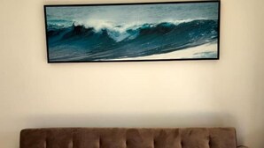 A room with a large framed ocean wave painting on the wall and a brown tufted sofa. - Lovely 2-bedroom rental in Carvoeiro free parking (Carvoeiro)