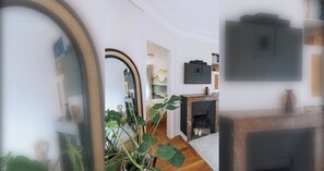 A modern living room with a fireplace, a television mounted on the wall, and a large mirror. - Unique & Luminueux - Appart 1 chambre- Montmartre! (Paris)
