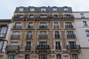 Um edifício de vários andares com estilo arquitetônico clássico, apresentando varandas ornamentadas e fachada uniforme.