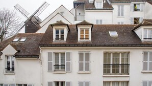 A row of white buildings with multiple windows and shutters, some with balconies.