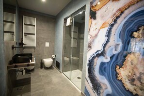 Une salle de bain moderne avec une douche à parois de verre, un lavabo intégré et un mur en marbre.