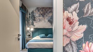 A bedroom with a teal bed, a large floral mural, and a nightstand with a lamp. - Green Diamond in Naples (Naples)