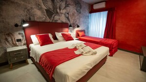 Una habitación de hotel con una cama grande, una cama más pequeña, una mesita de noche y una pared con un mural floral.