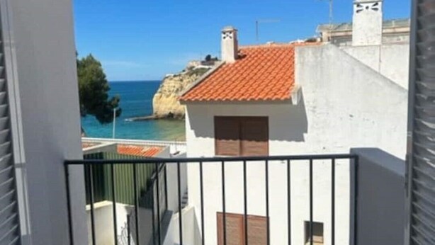 A balcony with a view of the sea and a building with a red-tiled roof. - 1bedroom duplex beach apartment (Carvoeiro)