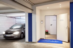 A hotel entrance with a blue mat, a car in the background, and a door labeled 'Hotel Imperial'.