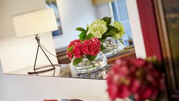 A room with a mirror reflecting a lamp, two flower vases, and a partial view of a chair.