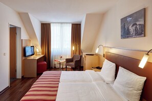 A hotel room with a large bed, a desk with a computer, a chair, a small table with a vase, and a painting on the wall. - Hotel Imperial Dusseldorf, Sure Collection by BW (Düsseldorf)