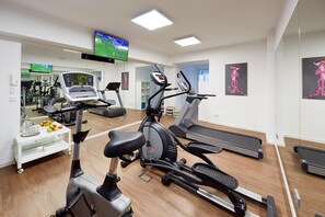 A fitness center with cardio machines, a TV screen, and motivational artwork. - Hotel Imperial Dusseldorf, Sure Collection by BW (Düsseldorf)