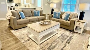 Ein Wohnzimmer mit einem beigen Sofa, einem Couchtisch und einem Teppich.