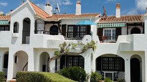 A white building with multiple balconies, arched doorways, and a tiled roof. - Apartment MULBERRY (Son Bou)