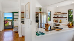 Eine moderne Küche mit Meerblick, Edelstahlgeräte und einer weißen Arbeitsplatte.