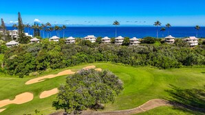 Ein Golfplatz mit Bunkern und freiem Blick auf den Ozean und Palmen.