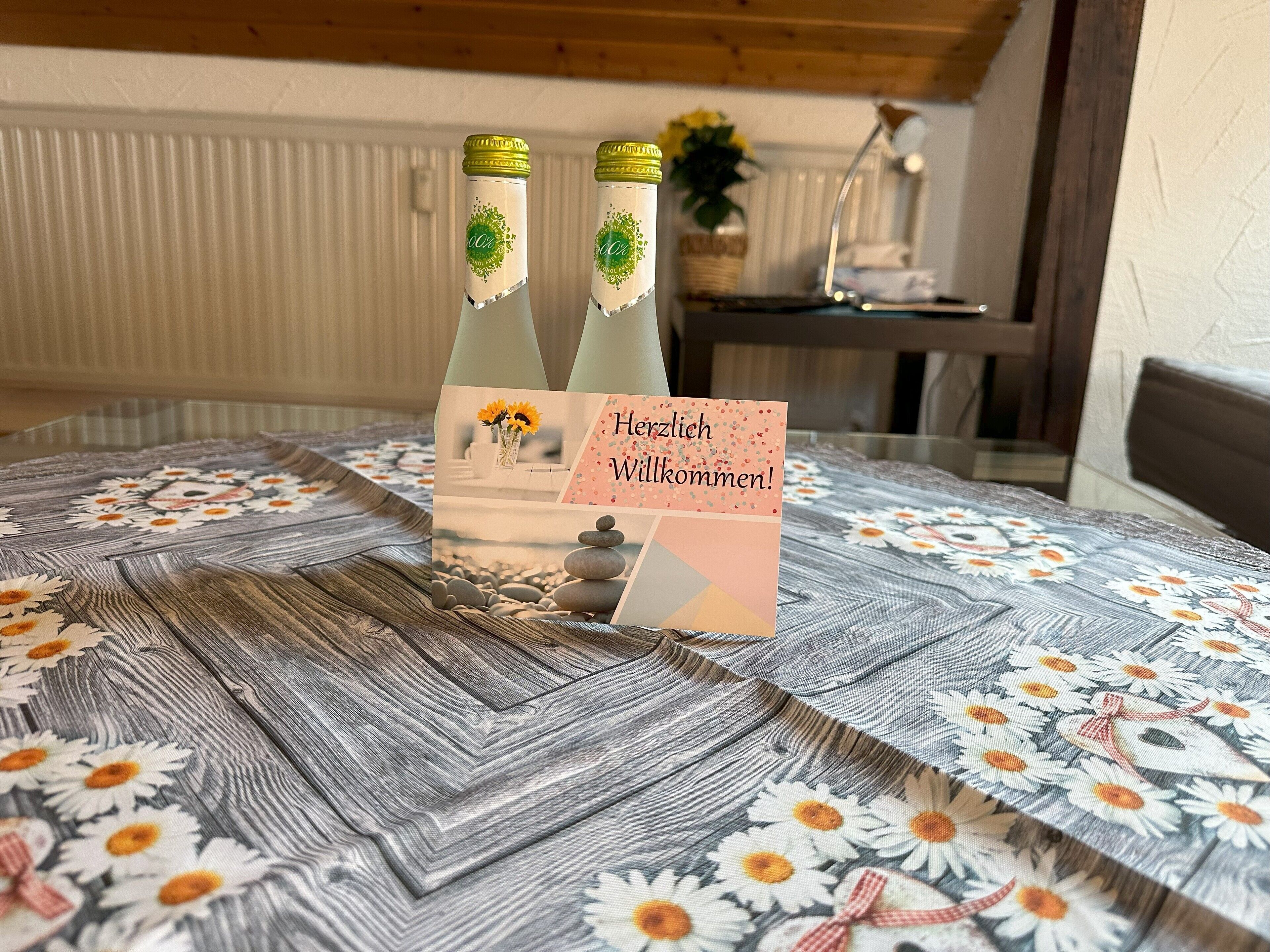 Uma mesa com toalha florida, duas garrafas de água e um cartão de boas-vindas.