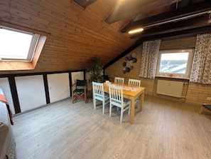 A dining area with a wooden table and chairs, a potted plant, and a view through a window. - Schöne, Geräumige Ferienwohnung im Wein- u. Wandergebiet, Freizeitpark I.d. Nähe (Löchgau)