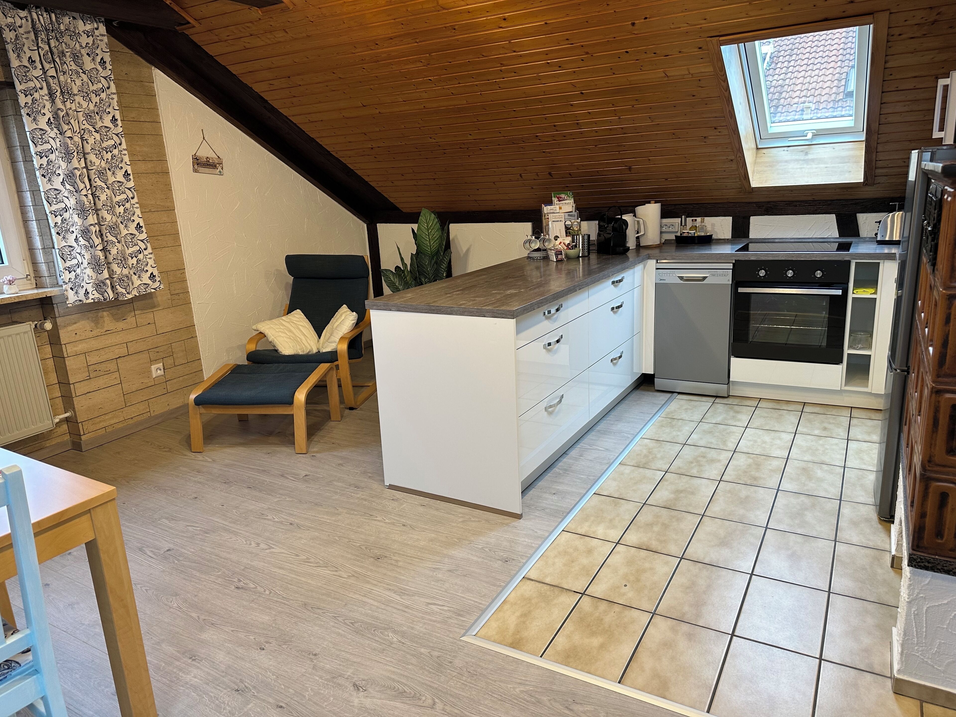 A kitchen with a central island, a dining area with a chair, a window with a view, and a skylight.
