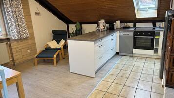 A kitchen with a central island, a dining area with a chair, a window with a view, and a skylight.