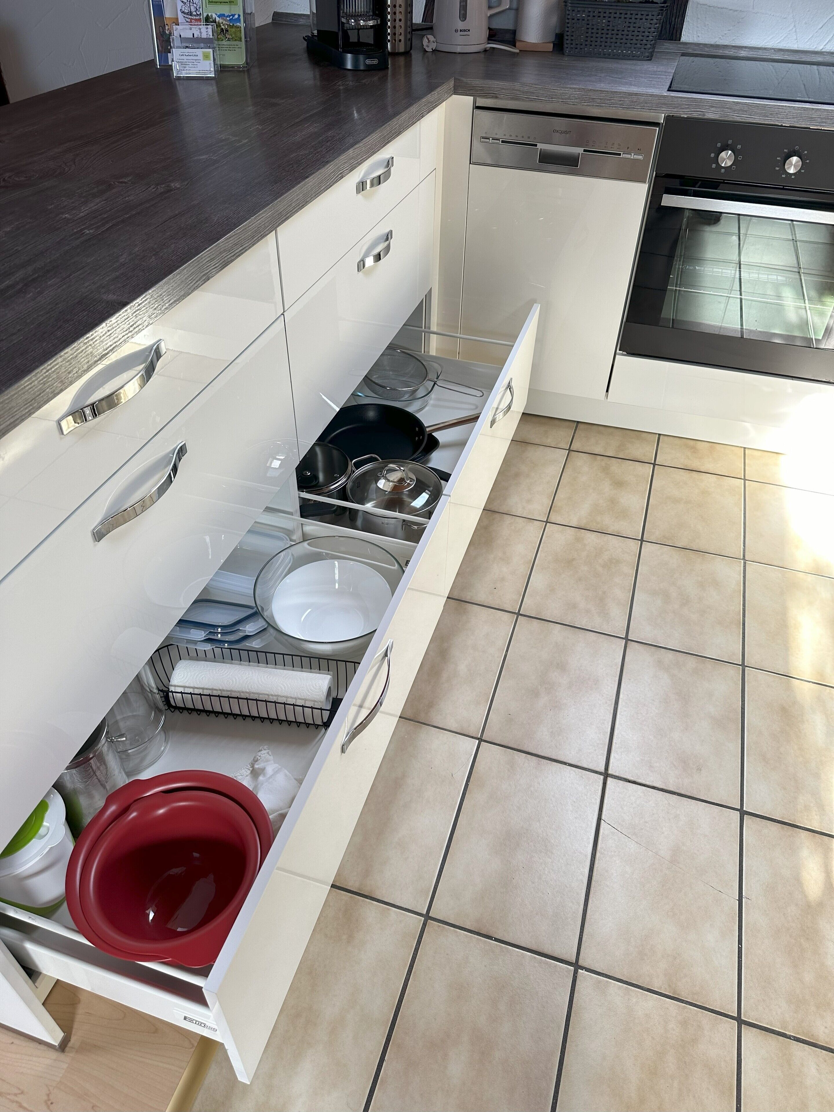 Cozinha com armários brancos, eletrodomésticos de aço inoxidável e piso revestido.