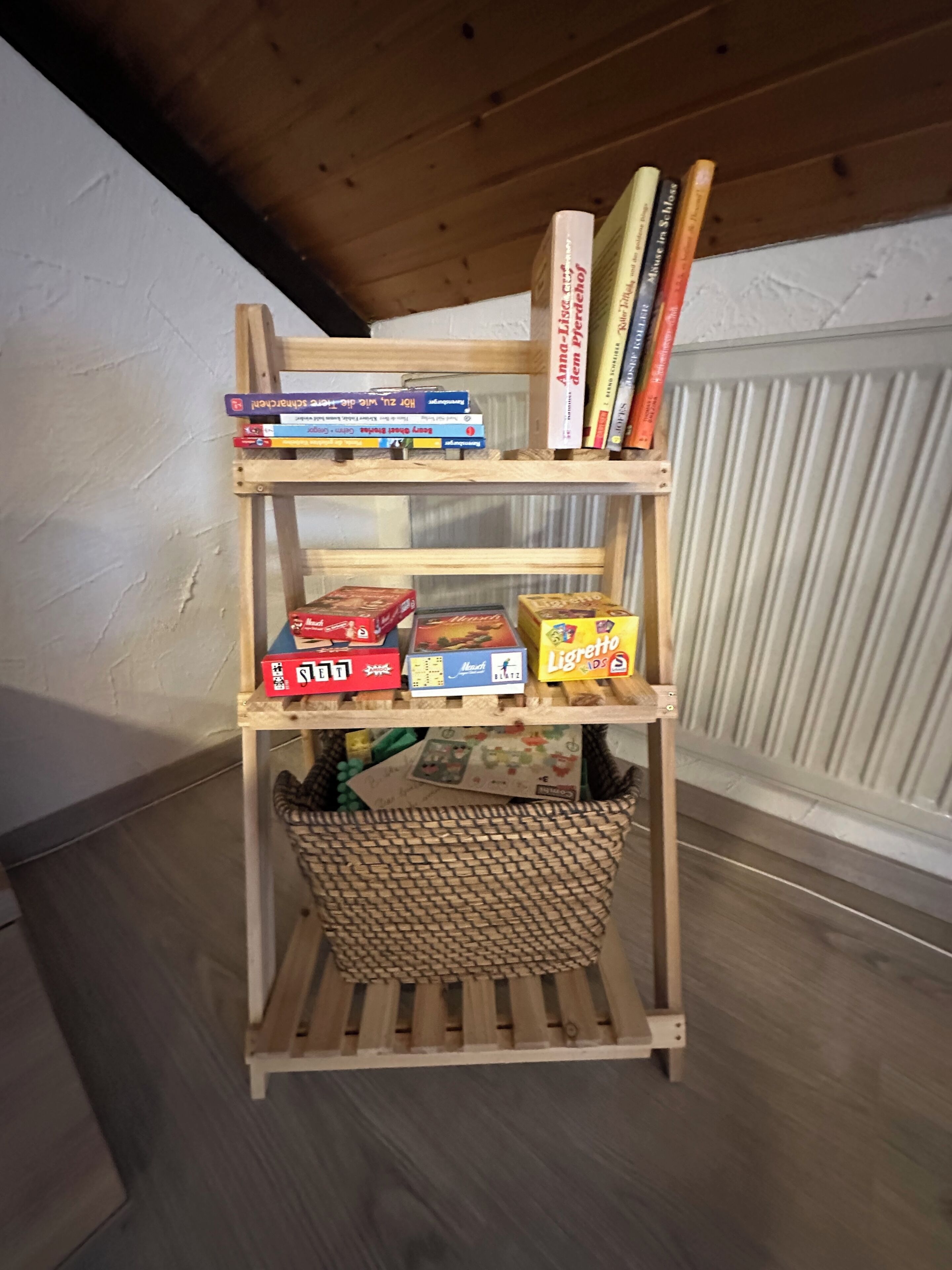 Uma estante de madeira com livros e jogos de tabuleiro.