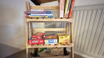 Uma estante de madeira com livros e jogos de tabuleiro.
