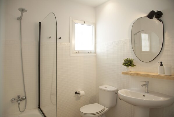 Ein Badezimmer mit Dusche, Toilette, Waschbecken und Spiegel.