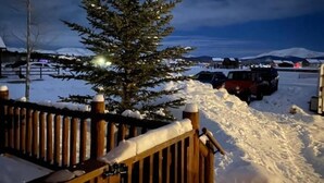 A snowy outdoor area with a wooden fence, a snow-covered tree, and parked vehicles. - Cozy Two Bedroom Cabin Mountain Getaway! (Fairplay)