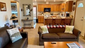 A living room with a brown leather sofa, a wooden coffee table, and a television. - Cozy Two Bedroom Cabin Mountain Getaway! (Fairplay)