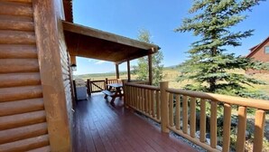 A wooden deck with a picnic table and grill, overlooking a scenic landscape. - Cozy Two Bedroom Cabin Mountain Getaway! (Fairplay)