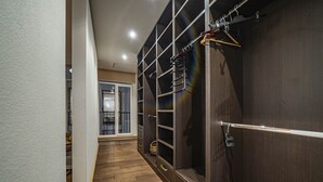 Ein Flur mit Holzboden, einem dunklen Holzschrank mit zahlreichen Regalen und Schubladen sowie einem Metallgestell mit Kleiderbügeln.
