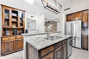 A modern kitchen with granite countertops, stainless steel appliances, wooden cabinets, and a skylight. - Family friendly transitional and modern designed home away from home (Grapevine)