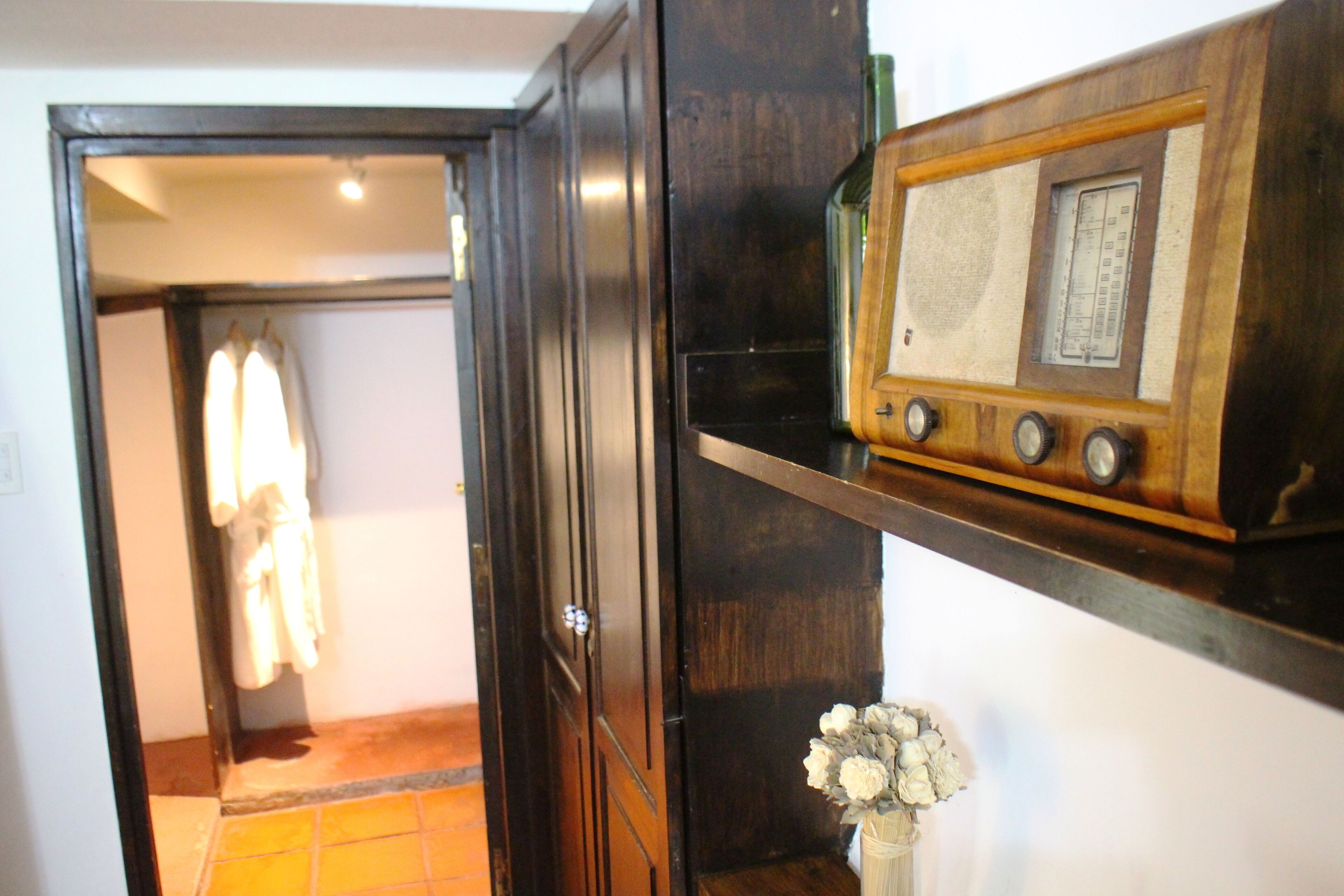 A wooden cabinet with a radio and a vase of flowers.