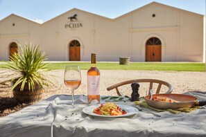 Mesa al aire libre con una botella de vino, una copa y un plato de pasta.