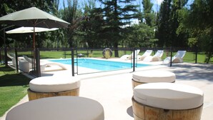 A poolside area with lounge chairs and wooden stools. - Posada La Celia (Eugenio Bustos)