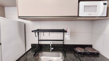Una kitchenette con microondas, pileta y cocina.