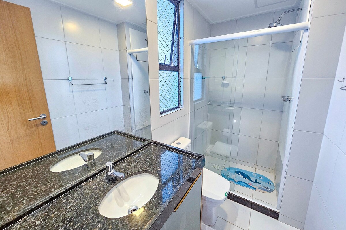 A bathroom with two sinks, a shower, and a toilet.