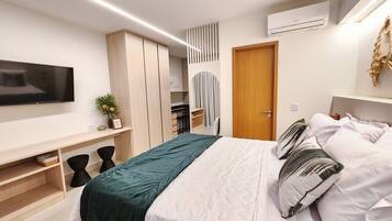 A modern bedroom with a bed, a TV, a wardrobe, and a desk.